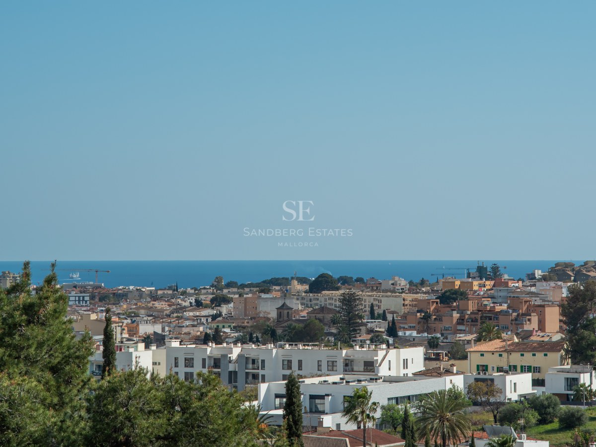 Vue d'en haut d'une ville côtière avec des bâtiments blancs et des toits rouges surplombant la mer Méditerranée.