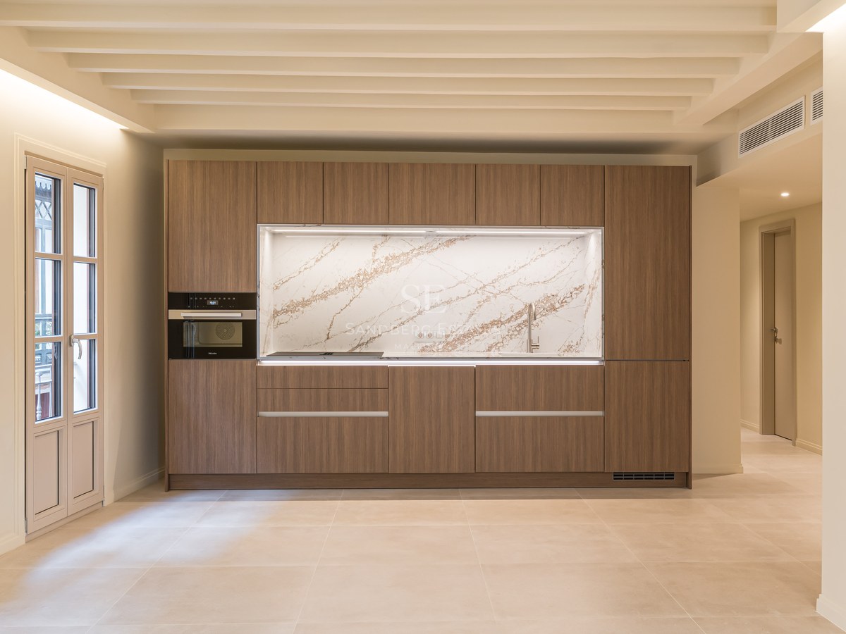 Cocina contemporánea con armarios de madera de nogal, frontal de mármol veteado y electrodomésticos integrados.