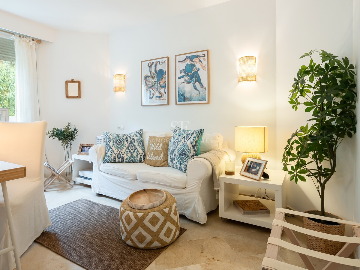 Bright living room featuring a white sofa, blue octopus wall art, marble flooring, and a large window overlooking greenery.