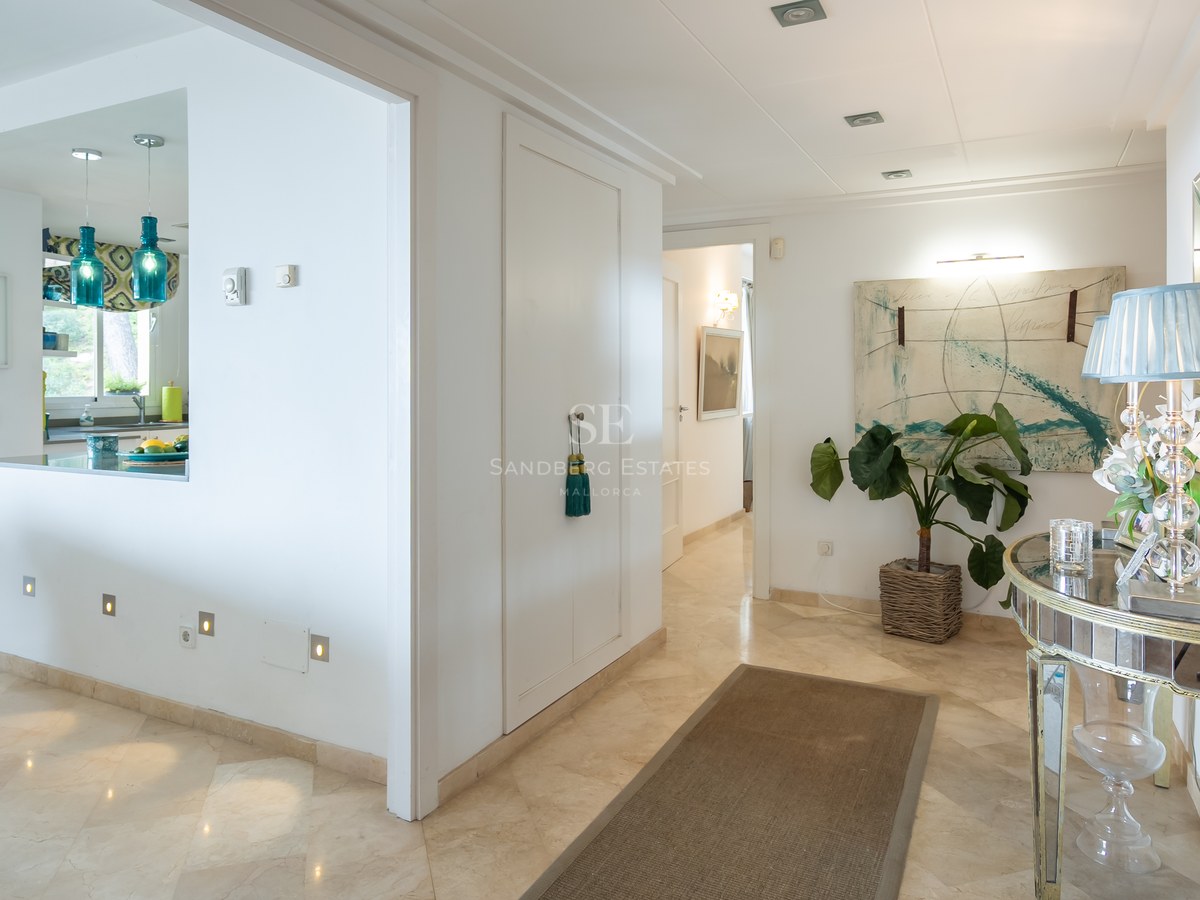 Bright entrance hallway featuring cream marble floors, a mirrored console table, and turquoise glass pendant lights.