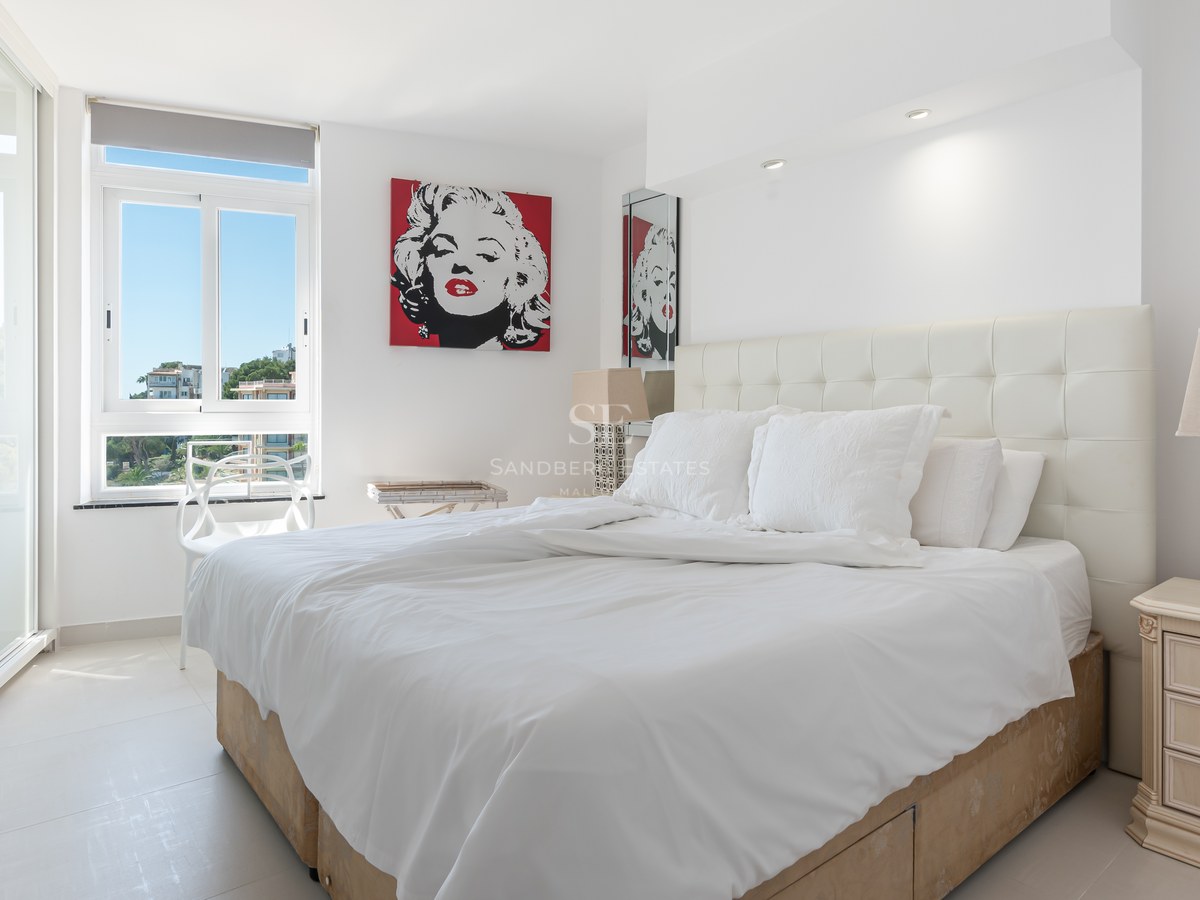 Modern bedroom featuring a white tufted headboard, large sliding glass doors, and vibrant pop art.