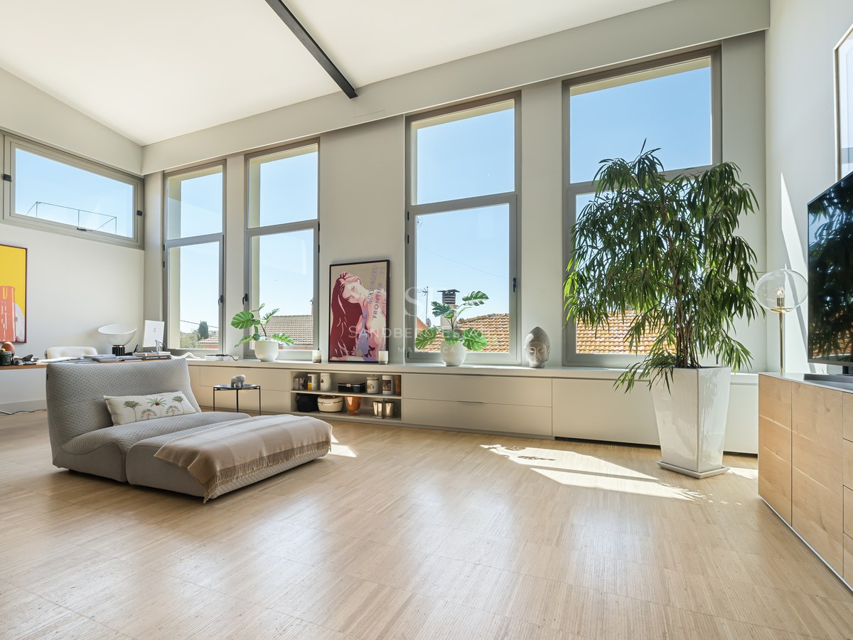 Heller Wohnraum mit Eichenparkett, großen vertikalen Fenstern, niedriger Liege und Pop-Art an weißen Wänden.