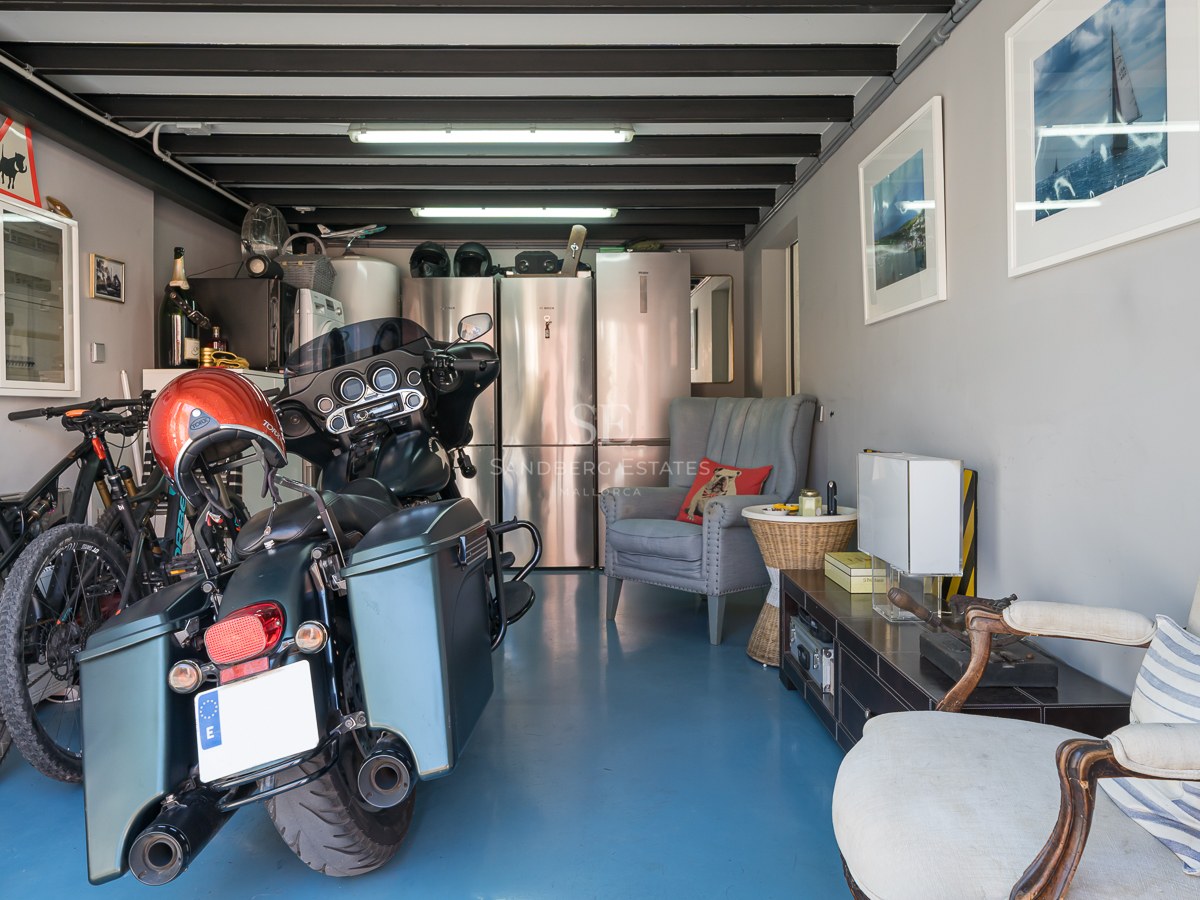 Garageninnenraum mit blauem Epoxidboden, Motorrädern, Fahrrädern und Edelstahlkühlschränken.