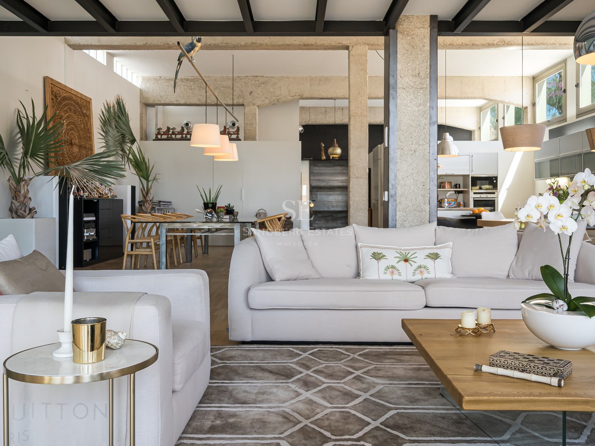 Modernes Wohnzimmer mit weißen Sofas, Sichtbetonpfeilern, schwarzer Industriedecke und hochwertiger Einrichtung.