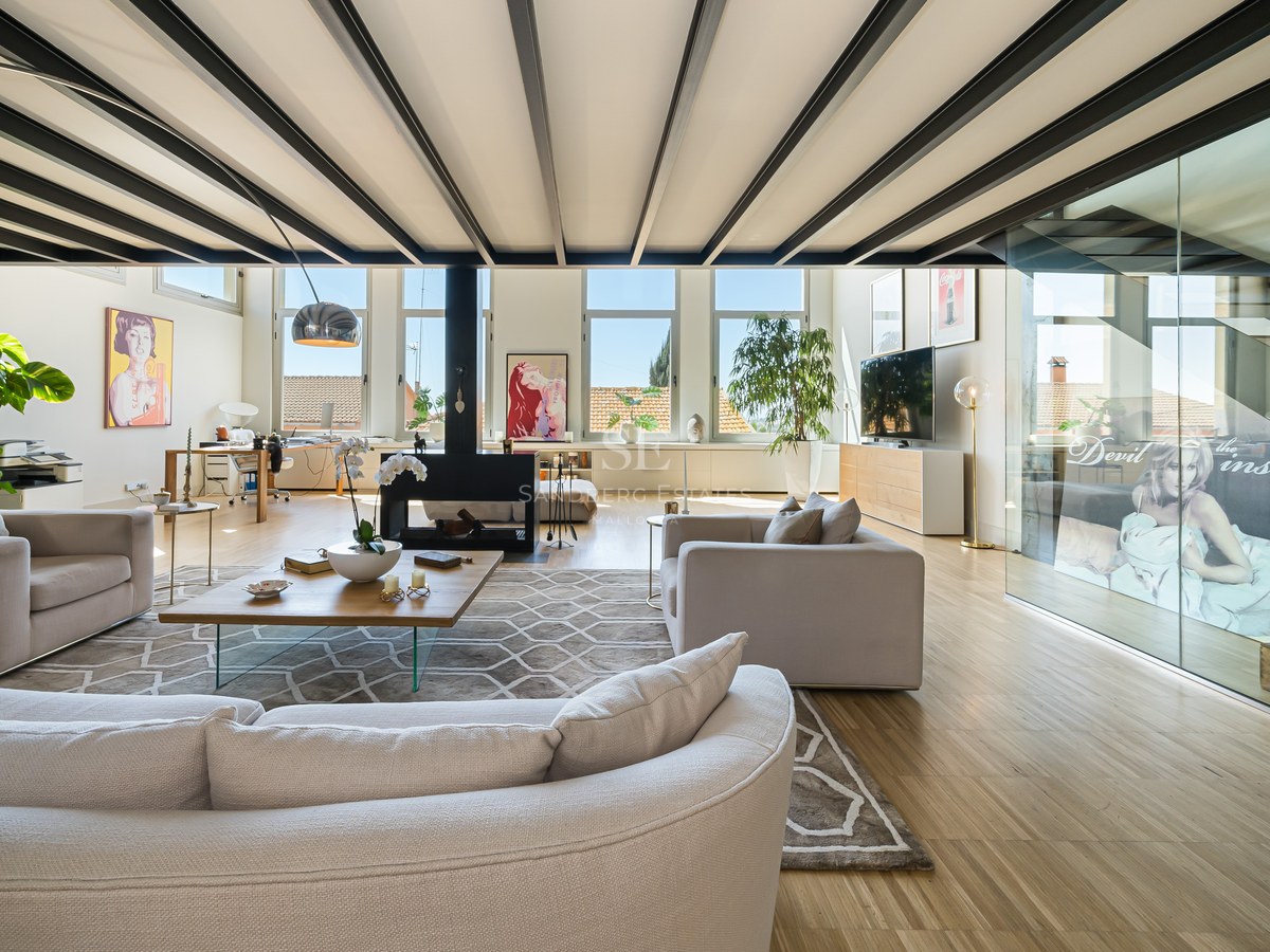 Helles Wohnzimmer mit schwarzen Stahlbalken, cremefarbenen Sofas, zentralem Kamin und großen Fenstern.