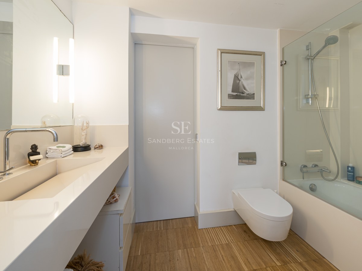 Modernes Badezimmer mit integriertem Waschtisch, wandhängendem WC und Badewanne mit Glastrennwand.