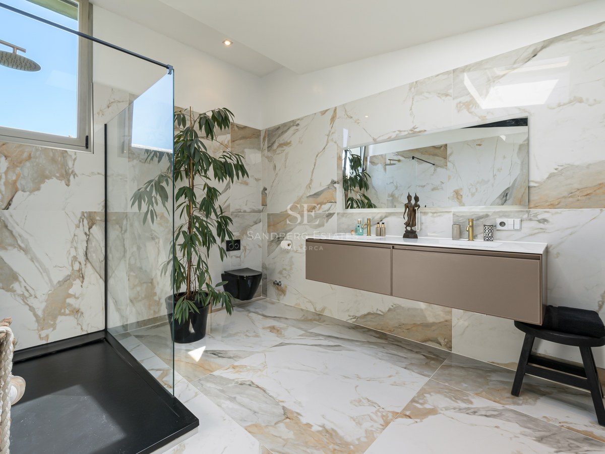 Luxus-Badezimmer mit Marmorwänden, begehbarer Glasdusche und schwebendem Doppelwaschtisch.