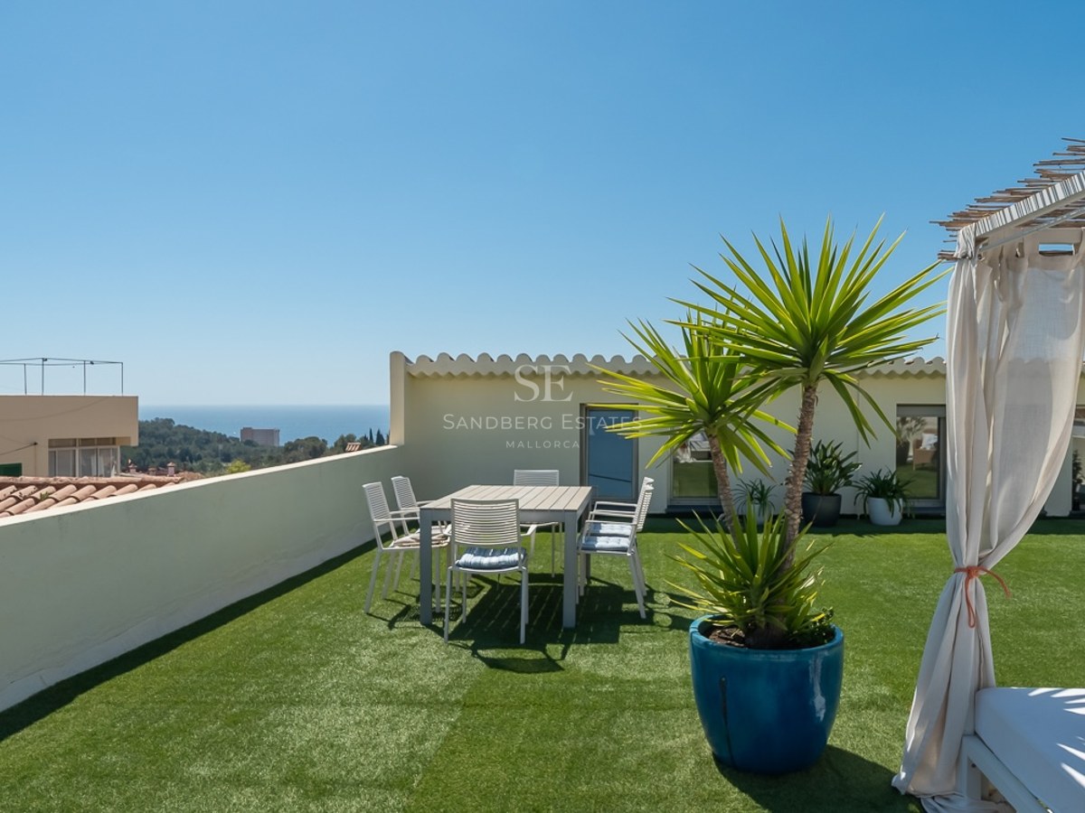 Dachterrasse mit Kunstrasen, Essbereich und einem Tagesbett mit Vorhängen und Blick auf das Mittelmeer.