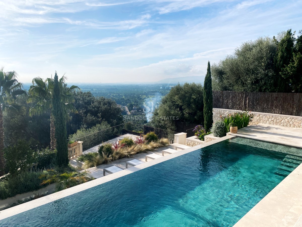 Türkisfarbener Infinity-Pool mit Blick auf eine üppige grüne Landschaft unter klarem blauem Himmel.