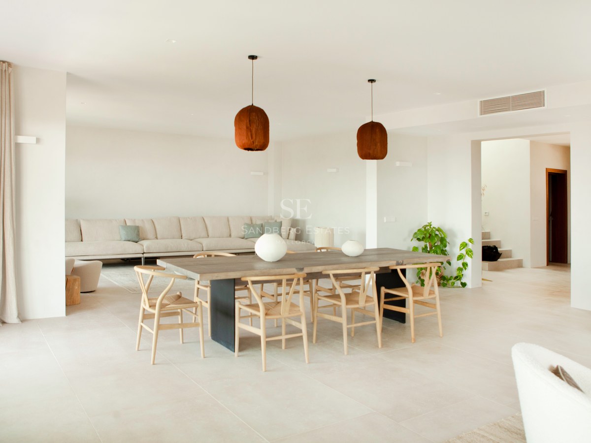 Heller, moderner Essbereich mit großem Holztisch, Wishbone-Stühlen und neutralem Sofa in offenem Grundriss.
