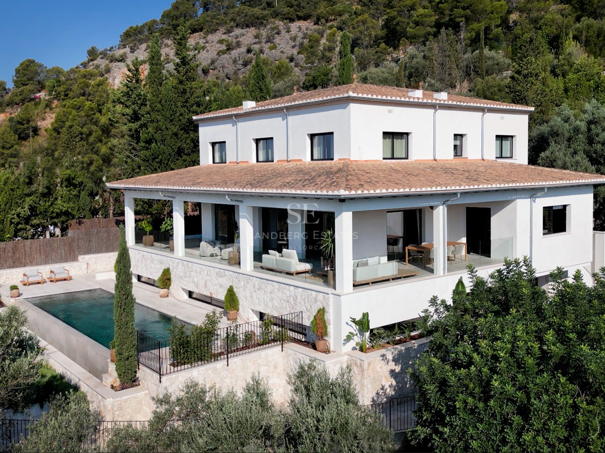 Erhöhte Ansicht einer weißen mehrstöckigen Villa mit Ziegeldach, Pool und Natursteinterrassen im Grünen.