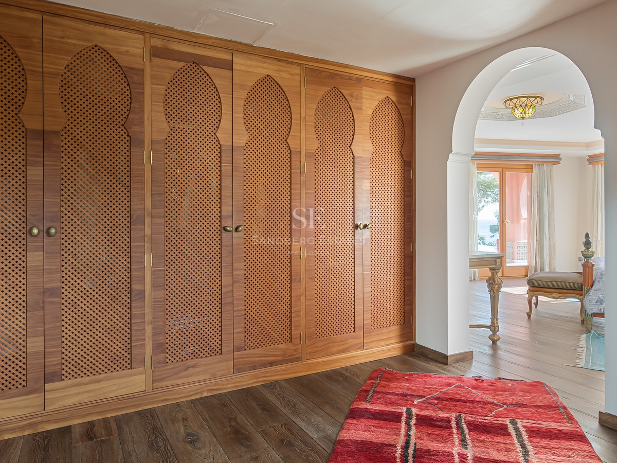 Gros plan de placards en bois du sol au plafond avec des détails d'arches mauresques et parquet foncé.