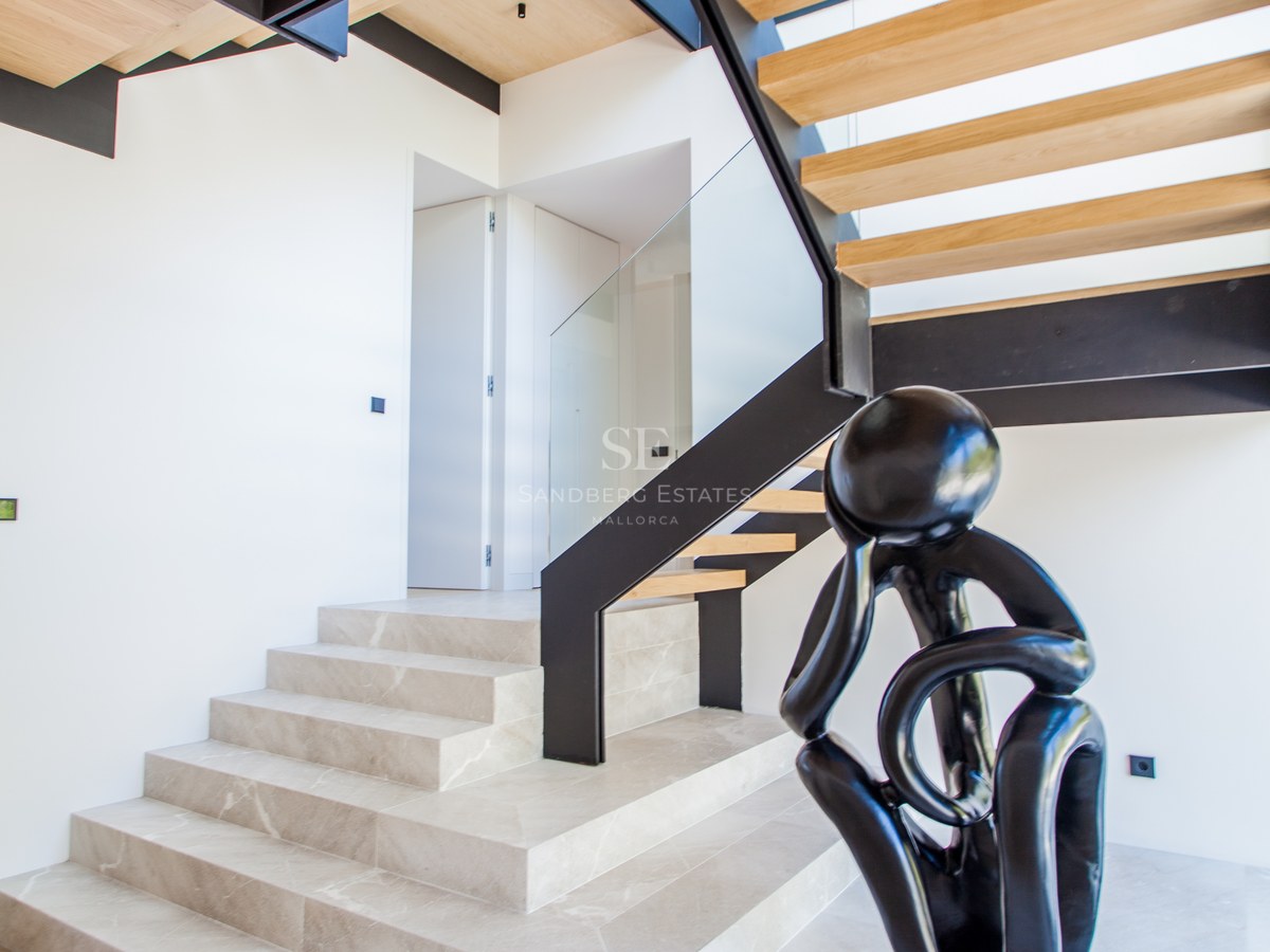 Moderne Treppe mit Steinstufen, schwarzem Stahlrahmen und Holzelementen neben einer schwarzen abstrakten Skulptur.