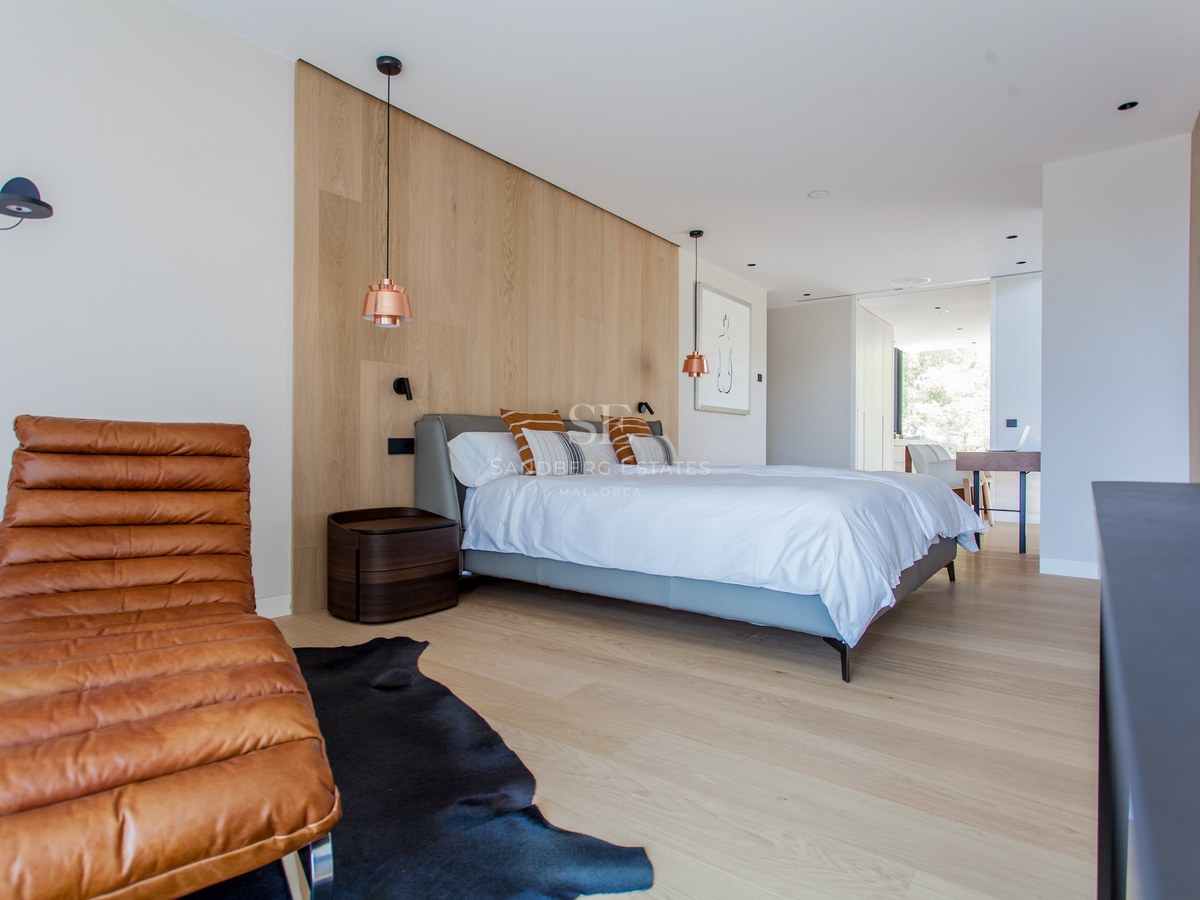 Zeitgenössisches Schlafzimmer mit Eichenwand, Leder-Chaiselongue und Kupfer-Pendelleuchten.