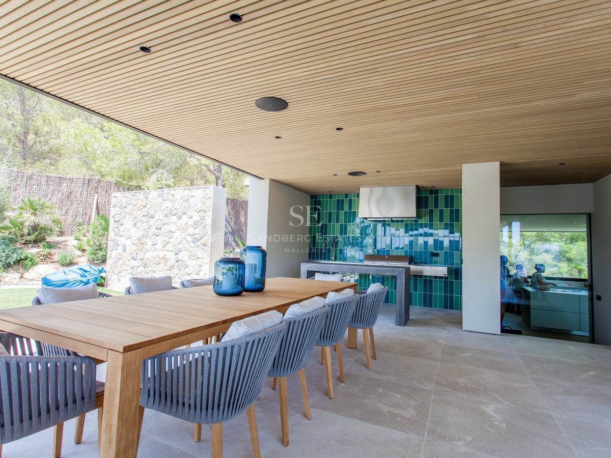 Moderne Terrasse mit großem Holztisch, Seilstühlen und einer voll ausgestatteten Außenküche mit grünen Fliesen.