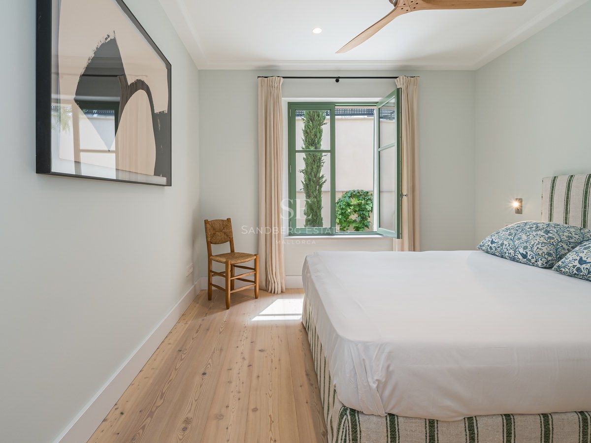 Dormitorio luminoso con suelos de madera clara, marcos de ventana verde salvia y textiles de lino natural.