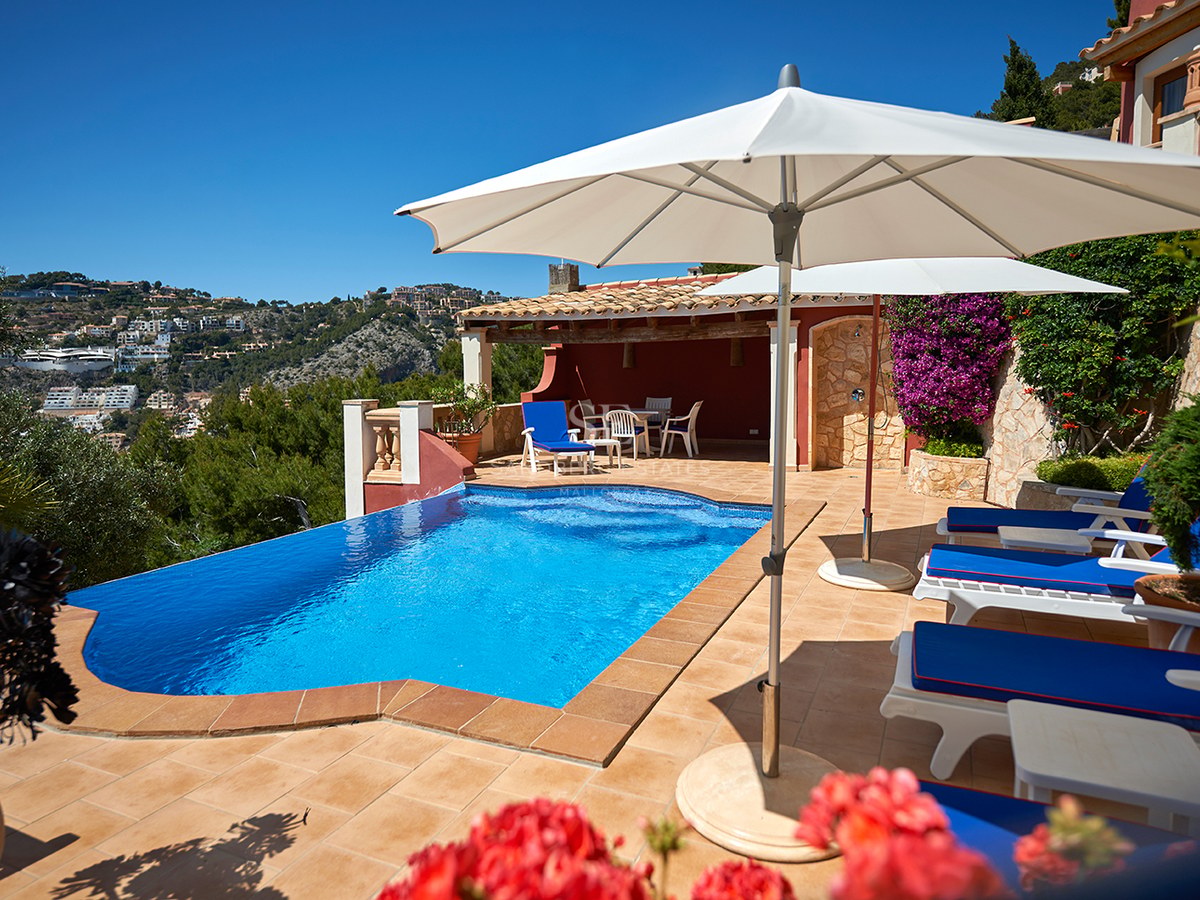 Private Poolterrasse mit blauen Sonnenliegen und weißen Schirmen mit Blick auf malerische Hügel.