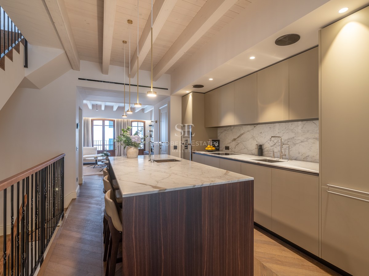 Cuisine moderne avec îlot central en marbre, parquet en chêne à bâtons rompus et poutres apparentes.