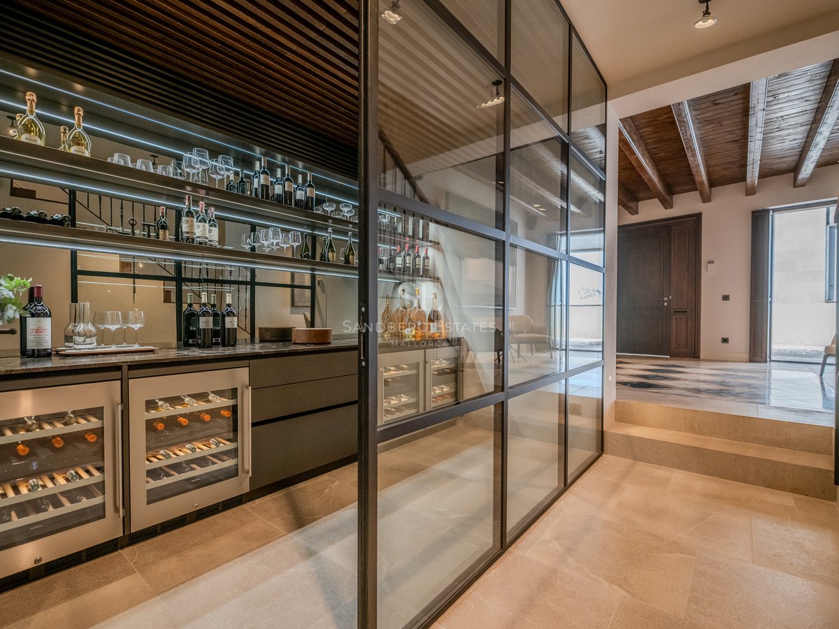 Cave à vin moderne avec parois en verre, cadres noirs, éclairage intégré et armoires à vin professionnelles.