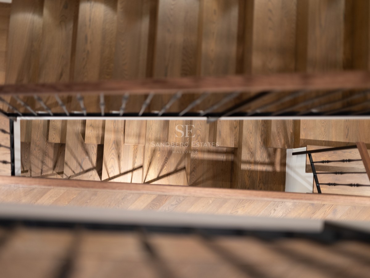 Vue de dessus d'un escalier en bois de chêne avec une rampe en fer forgé noir dans une propriété de luxe.