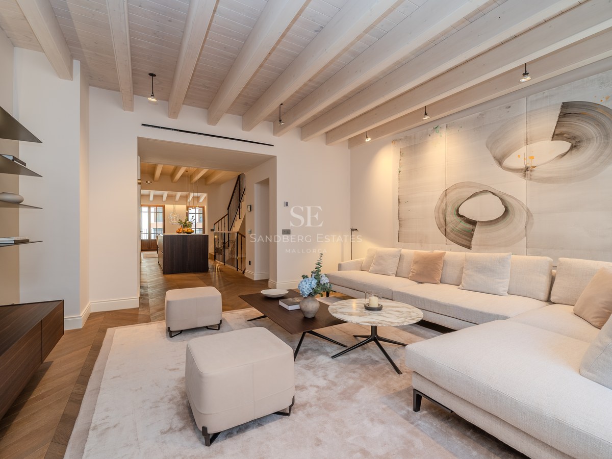 Salon moderne avec canapé crème, table en marbre, poutres en bois apparentes et parquet en point de Hongrie.
