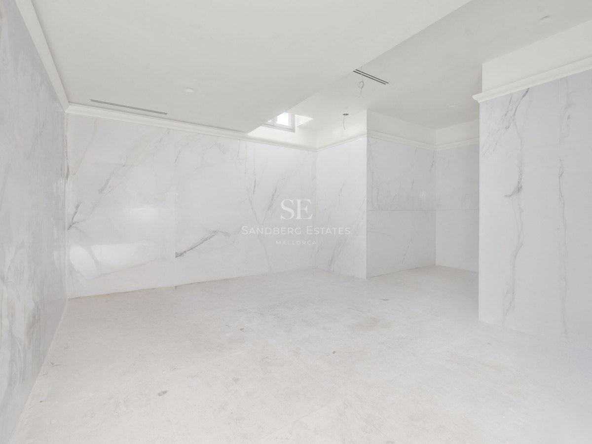 Baño de lujo en construcción con paredes y suelos de mármol blanco con vetas grises y techos con aire integrado.