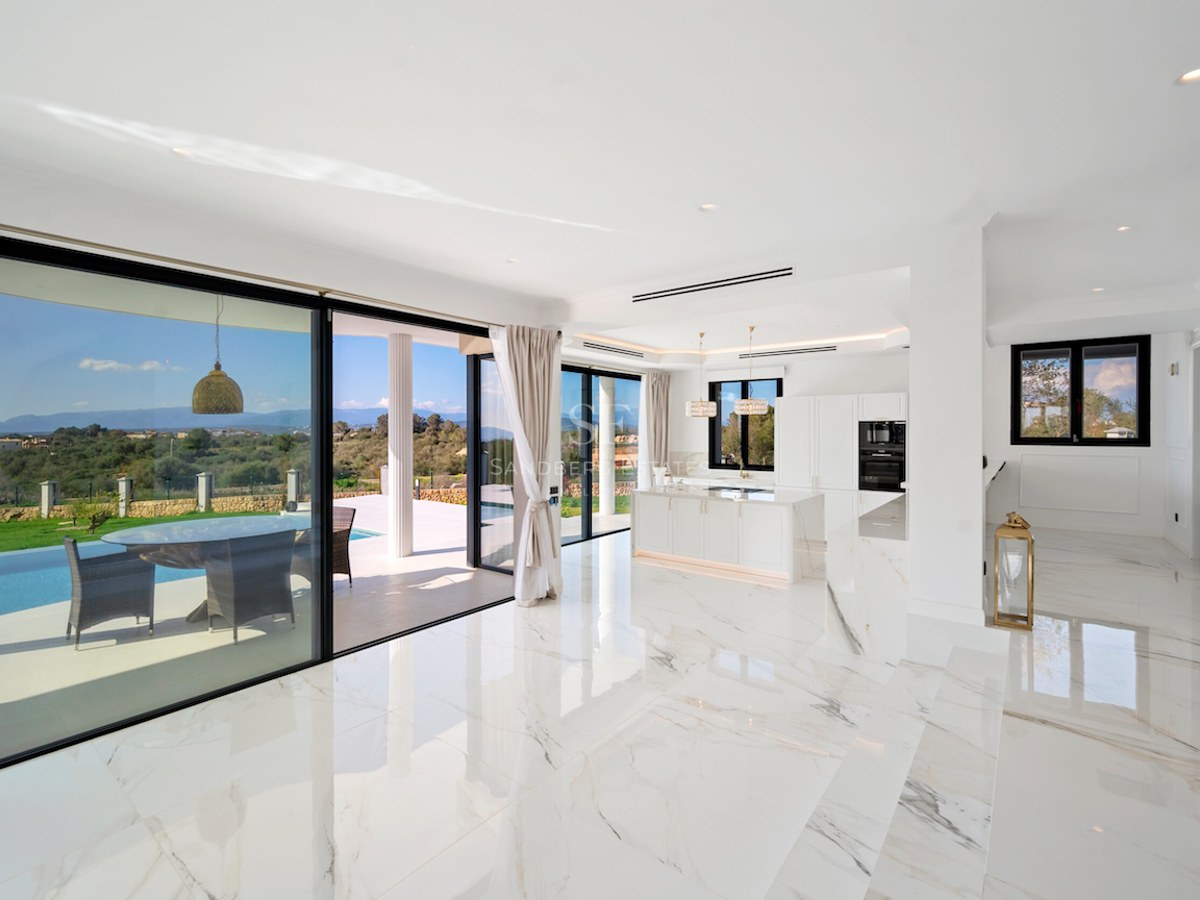 Salón moderno con suelos de mármol blanco y ventanales de suelo a techo que dan a una terraza con piscina.