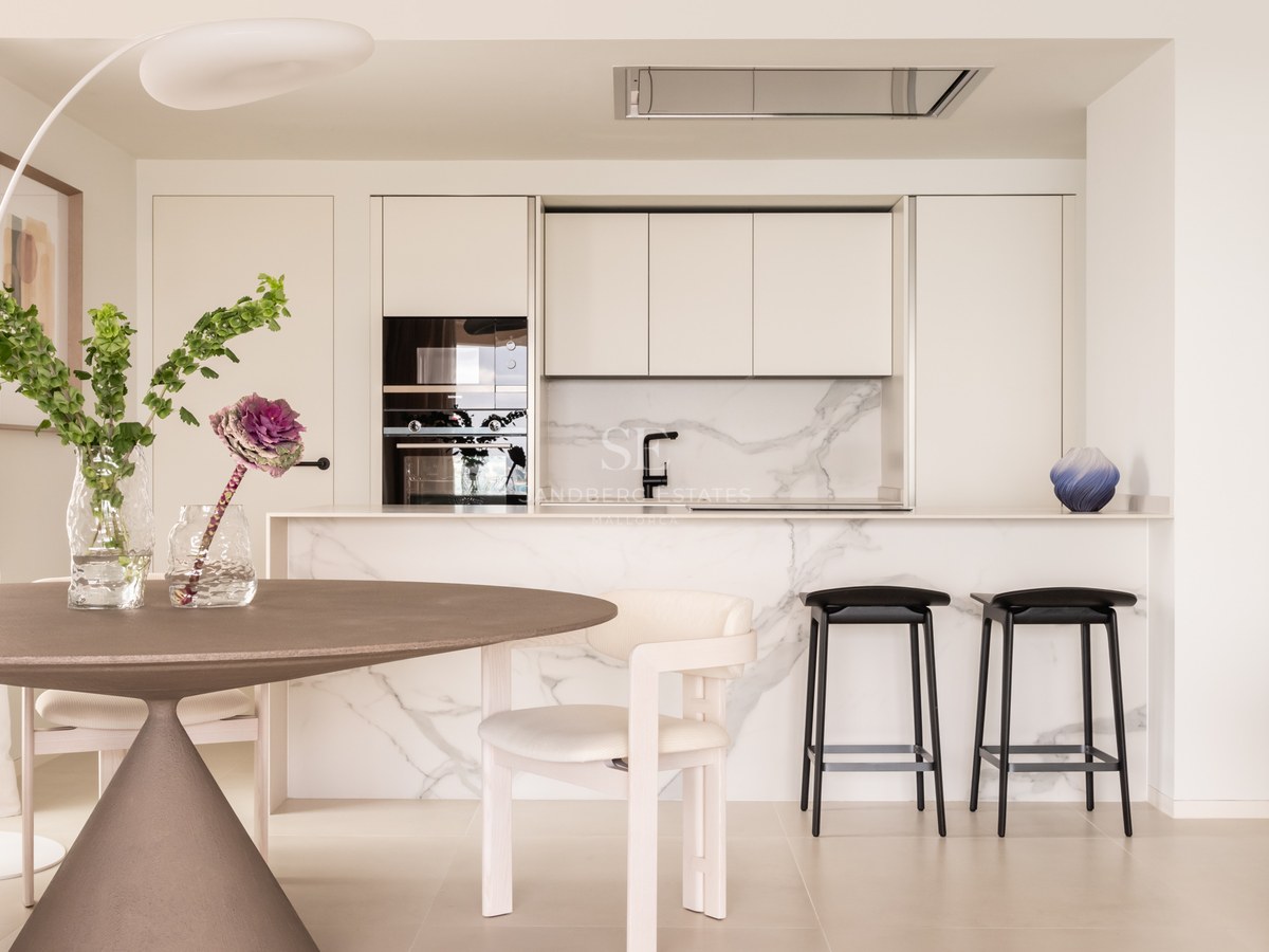 Minimalist kitchen featuring a Calacatta marble island, integrated appliances, and dining area with a round table.
