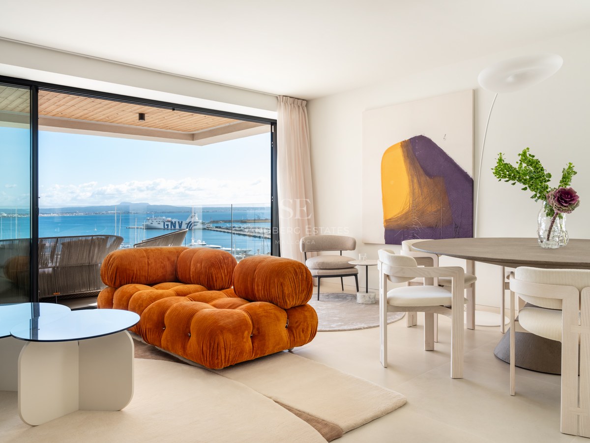 Modern living room with a burnt orange modular sofa, dining area, and large sliding doors opening to a sea-view terrace.
