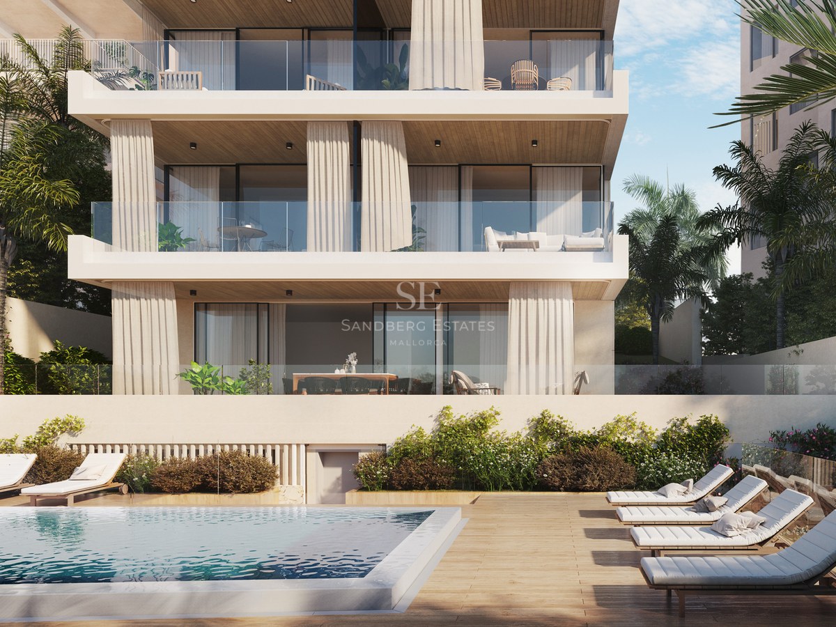 Luxury apartment building facade with a swimming pool, wooden deck with sun loungers, and multi-level glass terraces.