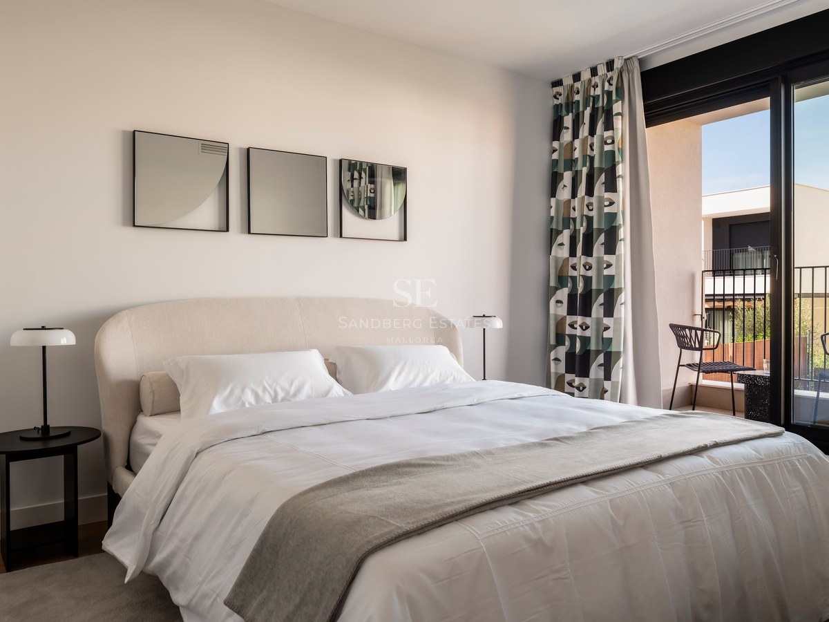 Chambre moderne avec lit rembourré, lampes design et baies vitrées ouvrant sur une terrasse.