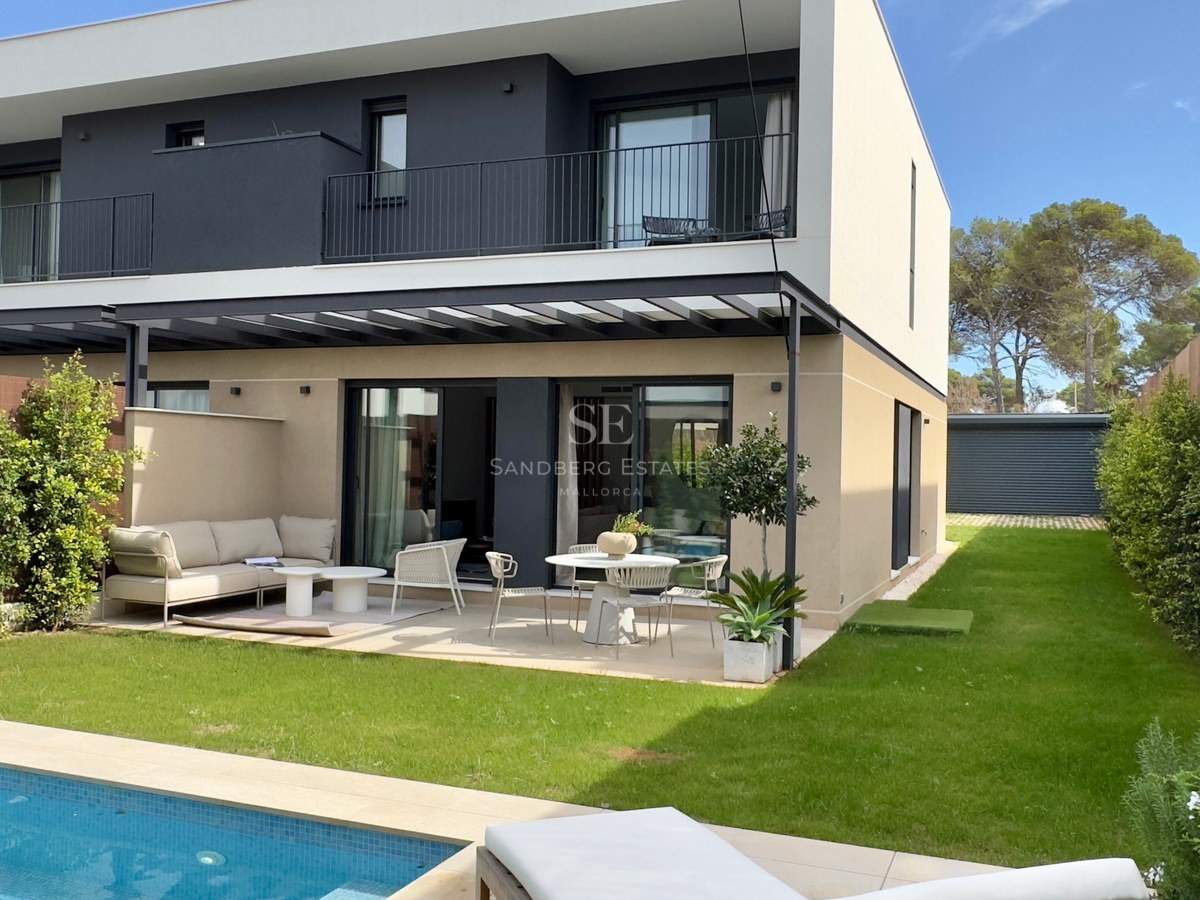 Extérieur d'une villa moderne blanche et grise avec terrasse, pelouse et piscine bleue au premier plan.