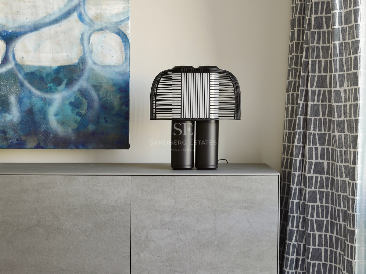 A grey stone-finish sideboard with a black designer lamp, an abstract blue painting, and patterned curtains.
