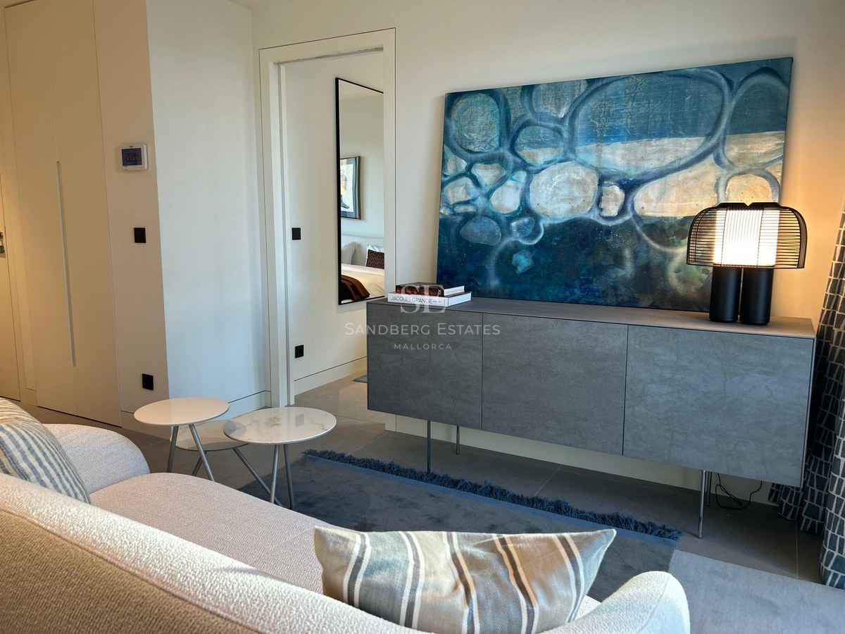 Modern living room corner featuring a grey sideboard, abstract blue art, a designer lamp, and marble side tables.