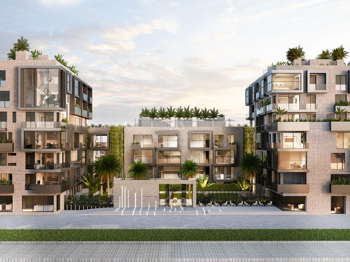 Luxury residential building with fair-faced concrete, floor-to-ceiling windows, and rooftop palm trees at dusk.