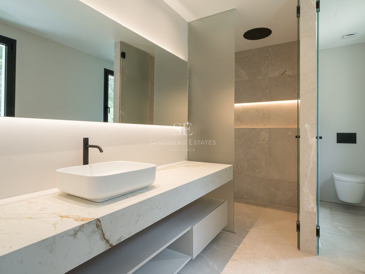 Baño contemporáneo con encimera de mármol, lavabo sobre encimera, ducha de efecto lluvia y sanitarios suspendidos.