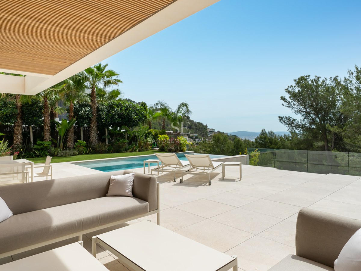 Terraza de lujo con suelo de piedra caliza, sofás de diseño, piscina infinita y vistas despejadas a la costa.