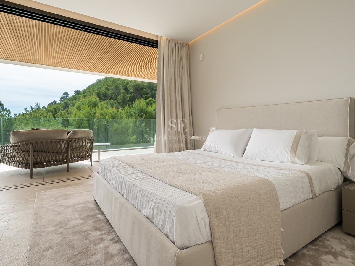 Suite principal contemporánea con puertas correderas que dan a una terraza con techo de madera y vistas al bosque.