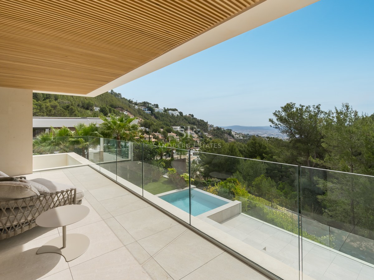 Terraza moderna con barandilla de cristal, suelo de piedra y techo de madera con vistas a la montaña y piscina.