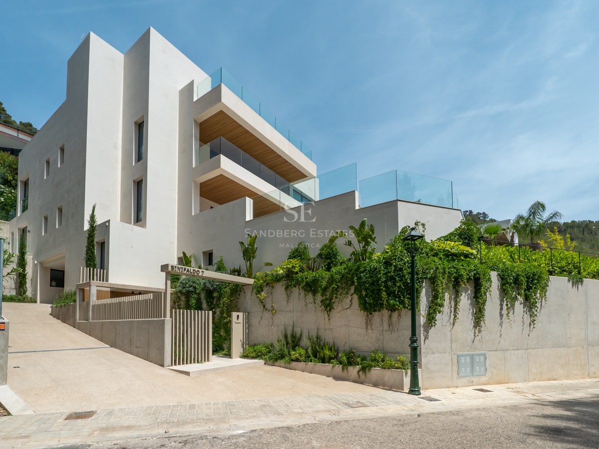Fachada de villa moderna de varios niveles con paredes blancas, barandillas de cristal y techos de madera.