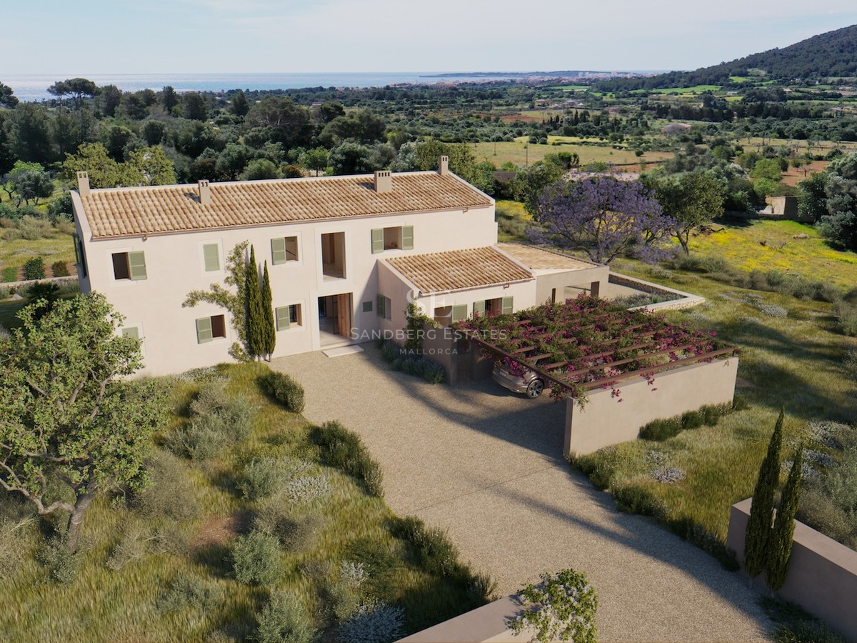 Erhöhte Ansicht einer beigen zweistöckigen Villa mit Terrakottadach, grünen Fensterläden und Kieseinfahrt am Meer.