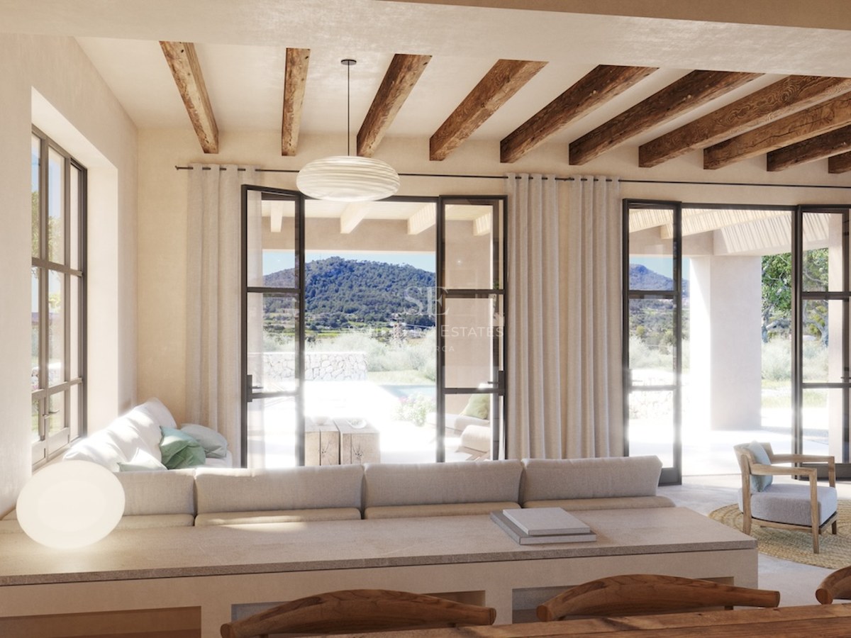Großzügiges Wohnzimmer im modernen mediterranen Stil mit Sichtbalken, schwarzen Fensterrahmen und Blick auf die Berge.