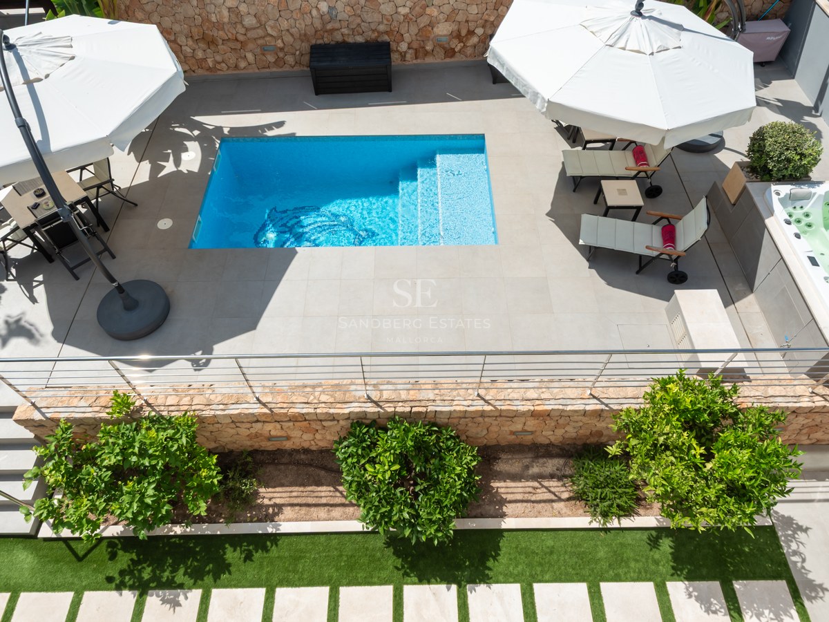 Flygvy över en turkos pool, integrerad jacuzzi och solstolar på en stenlagd terrass.