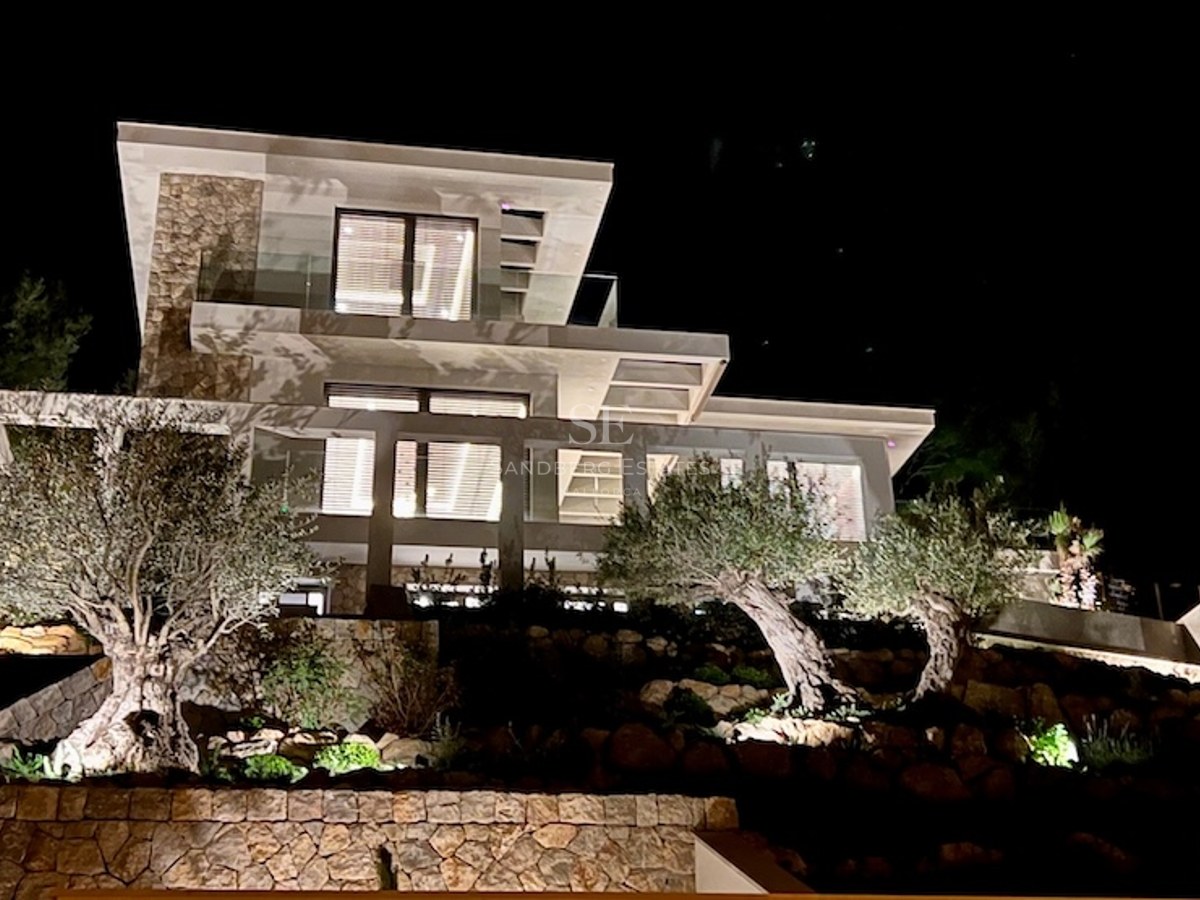 Imagen de chalet moderno con piscina, rodeado de vegetación. Diseño minimalista y acabados de lujo. Iluminación natural destacada.