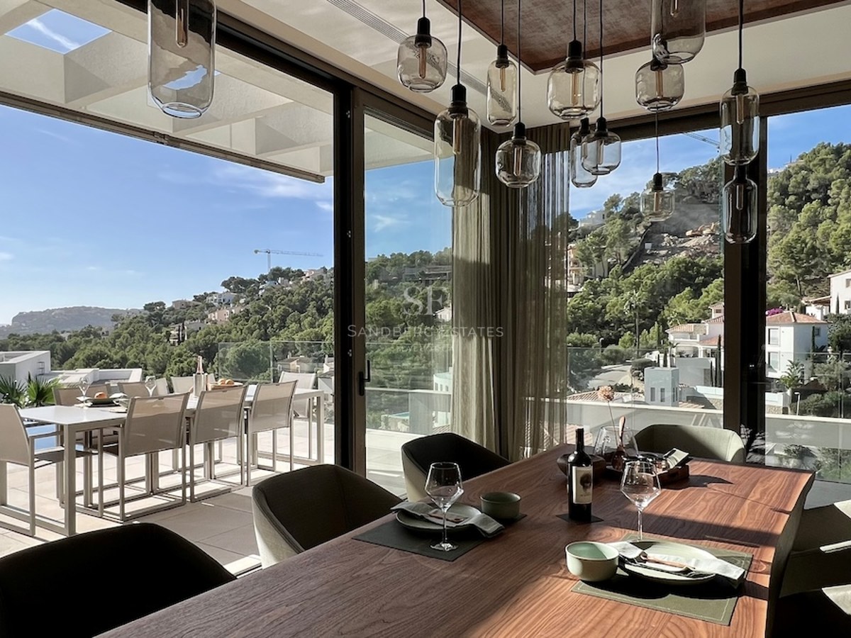 Amplia terraza con piscina infinita y vistas panorámicas al mar. Diseño moderno con mobiliario elegante y exuberante vegetación.