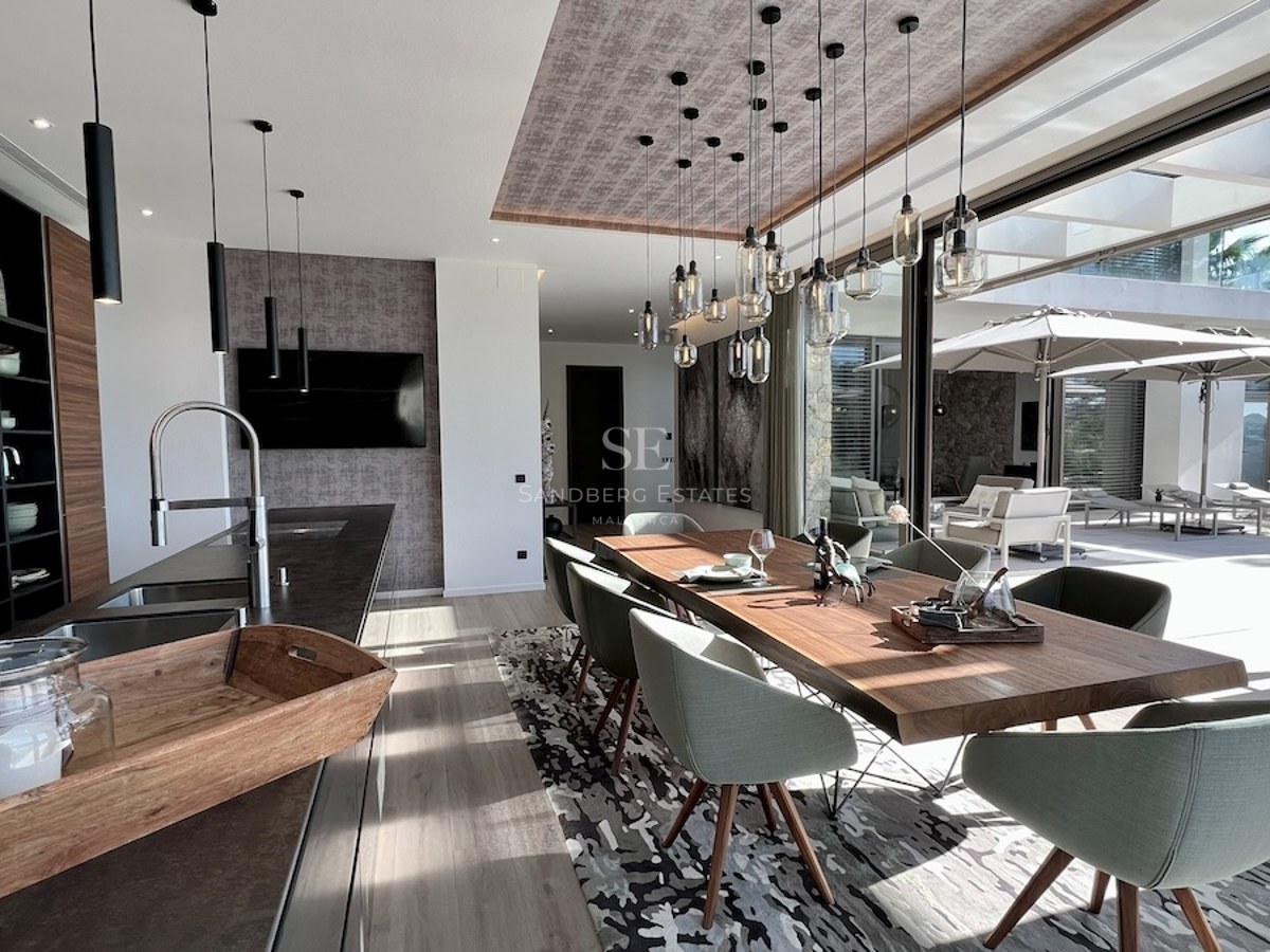 Ático moderno con balcón acristalado, vistas al mar y diseño minimalista. Iluminación natural y paleta de colores neutros.