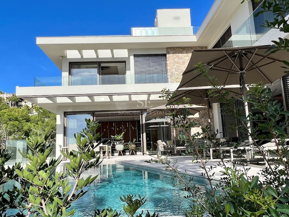 Imagen de fachada moderna con piscina y jardín. Diseño minimalista, amplios ventanales, iluminación cálida y vegetación exuberante.
