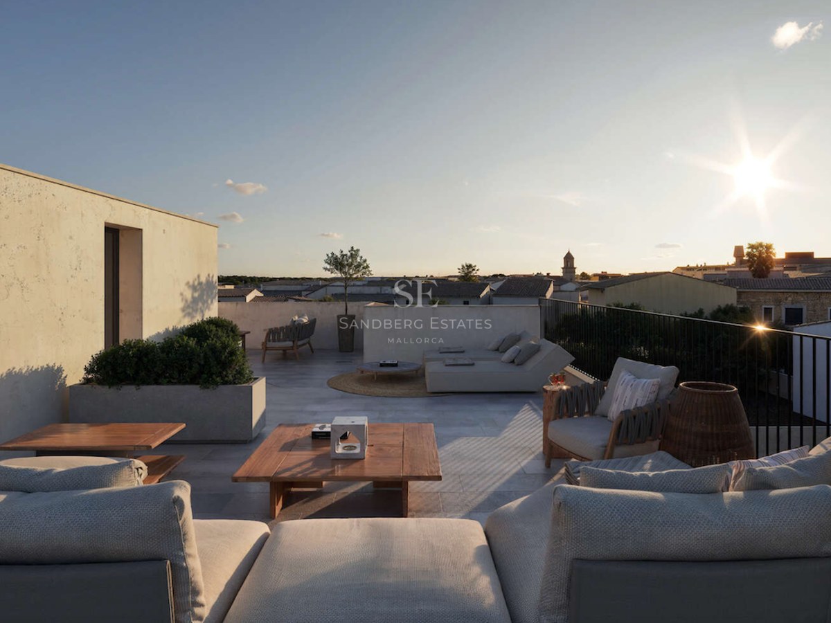 Terrasse de luxe avec sol en pierre naturelle, meubles en bois et transats surplombant une ville méditerranéenne.