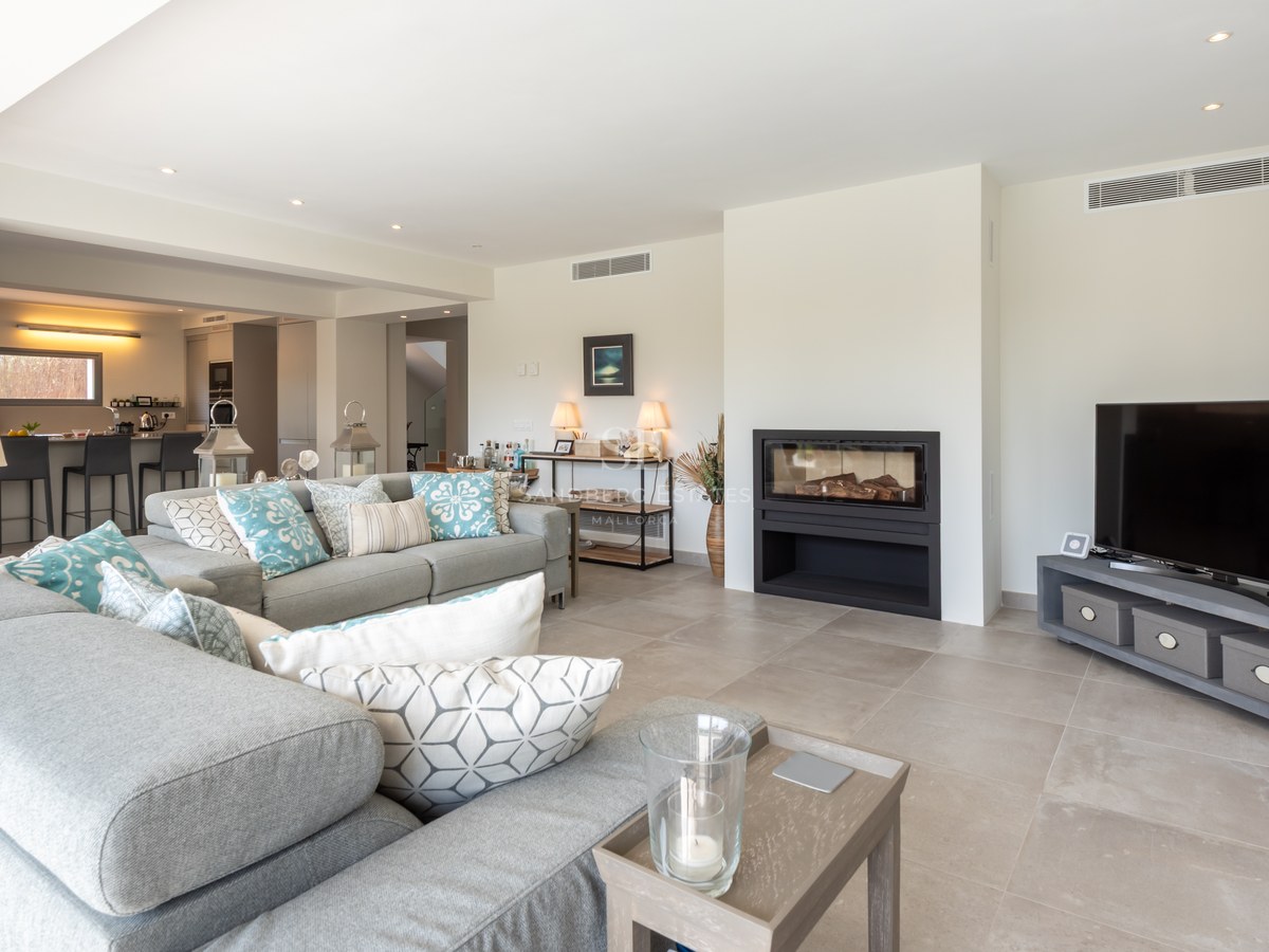 Spacious modern living room with grey sectional sofa, built-in fireplace, and views into the open kitchen.