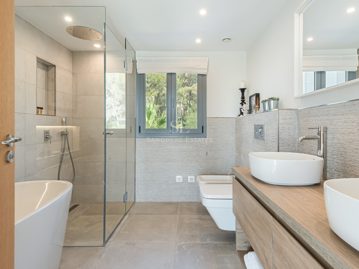 Modern bathroom featuring a glass walk-in shower, freestanding tub, and double vessel sinks on an oak vanity.